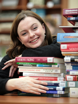 Renee leaning on a pile of books in the browsing library