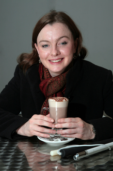 Renee sitting in the Kooyong cafe with a hot chocolate and white cane on the table