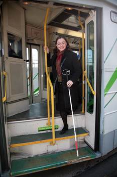 Renee disembarking from a tram with her white cane