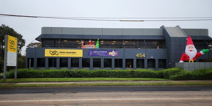 Side view of Glenferrie Road building decorated with a banner, inflated oversized Santa and smaller sized Santa with reindeer and Christmas tree. 