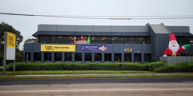 Side view of Glenferrie Road building decorated with a banner, inflated oversized Santa and smaller sized Santa with reindeer and Christmas tree. 