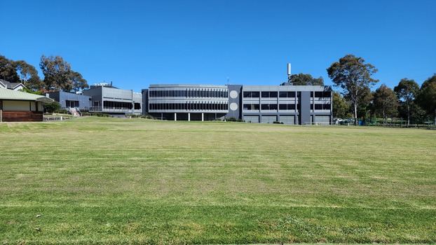 Oval with small building to left and large building behind it
