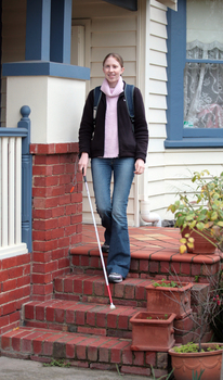 Anna leaving a house using her cane
