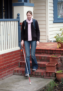 Anna leaving a house using her cane