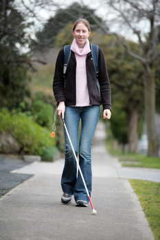 Anna walking along a footpath with her cane