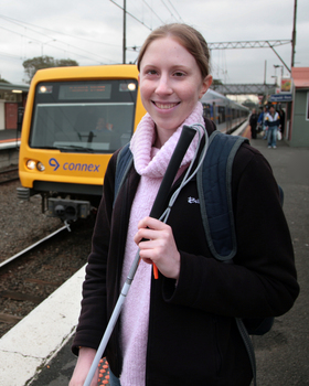Anna waiting on the platform with a train behind her
