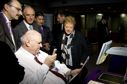Jim Pipczak demonstrating a Nokia screen reader to John and Nancye Cain, with Tony Iezzi, unknown staffer and Tim Evans looking on