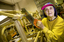 Elderly woman stands in a workshop with a saw in her hands