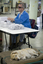Man packaging items at a bench whilst his dog is lying on a pet bed