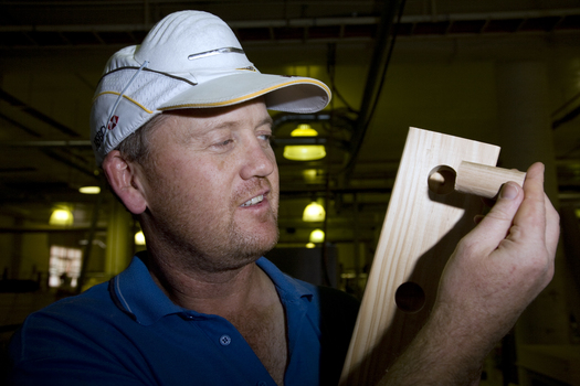Man holding a piece of dowel and a wooden block