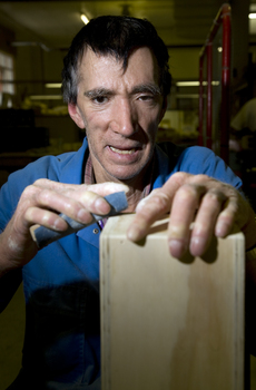 Man is hand sanding a block of wood