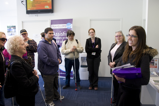 White cane users listen to directions in the Travellers Aid office