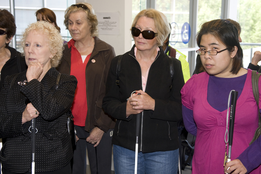 White cane users listen to directions in the Travellers Aid office