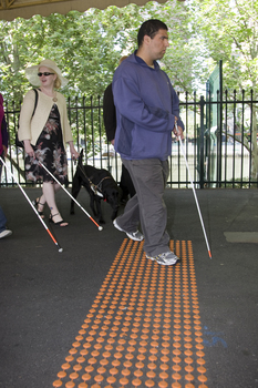 White cane users walking along the train platform