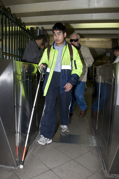 Male white cane user navigates the ticketed entry