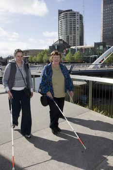 White cane users walking along river path at Southbank on a sunny day