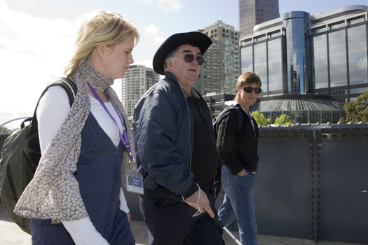 White cane user walking along river path at Southbank on a sunny day