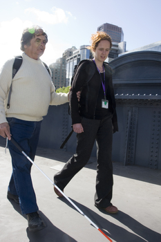 White cane user crossing bridge at Southbank on a sunny day