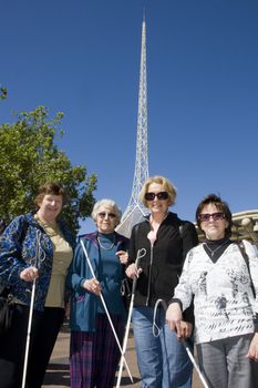 Group of white cane users pose with Arts Centre spire in background