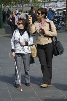 White cane user looking at Southbank shopping precinct on a sunny day