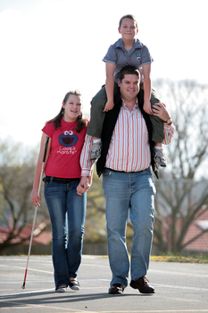 Tony Clarke with his son and daughter walking in a schoolyard