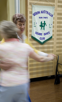 The Square Dance Club banner on the wall as people dance by