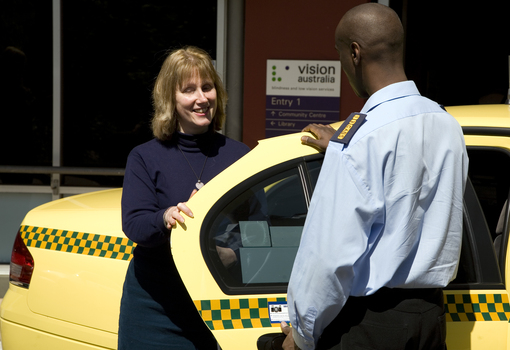 Taxi driver assisting a woman with a white cane 