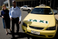 Taxi driver assisting a woman with a white cane 