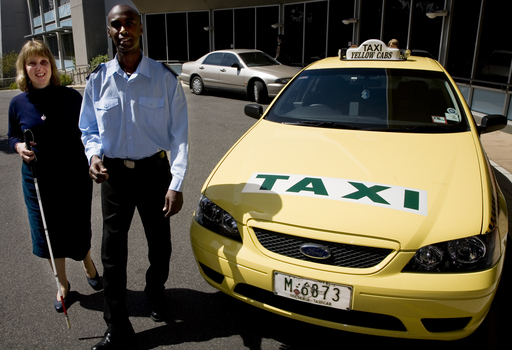 Taxi driver assisting a woman with a white cane 