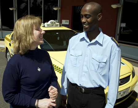 Taxi driver assisting a woman with a white cane 