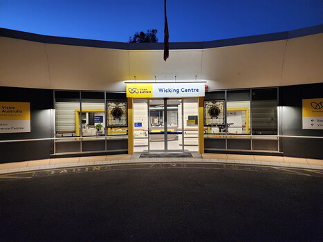 Front view of 'Wicking Centre' sign above main doorway from driveway