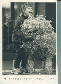 Girl smiling as she feels a sculpture of a lion made from hay and wire
