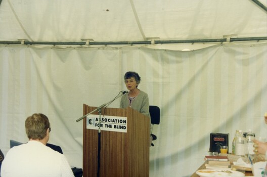 Female reading at podium to audience
