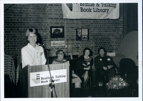 Meme McDonald at the podium with Lorna Hayted, Rose Blustein and Arnold Zable looking on