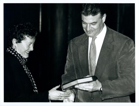 Rose Blustein being presented with a book by a male
