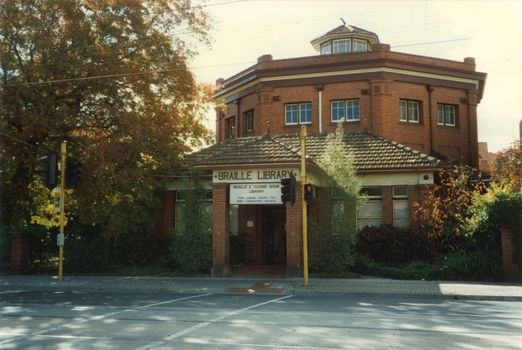 Red octagonal brick building facing pedestrian crossing and roadway