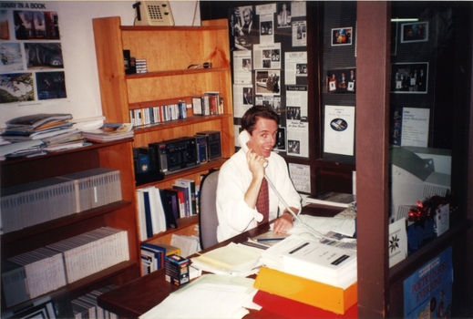 Karl Hughes on the phone surrounded by audio reels and tapes