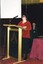 Braille Book of the year female judge at podium with Rose Blustein in the background