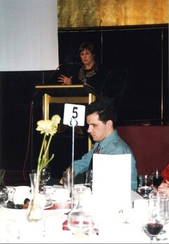 Deidre Rubenstein at the podium for the award ceremony with Glen Morrow in the foreground