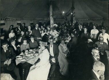 A large group of people in a tent, seated at tables