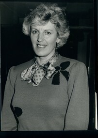 Woman wearing a knit jumper with bows, and patterned blouse with tied neckline