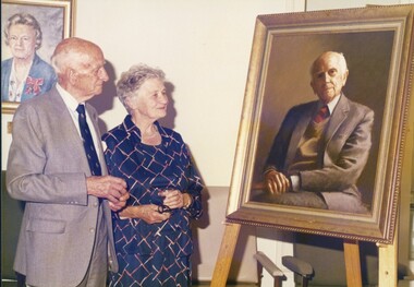 Pat and Beth Lightfoot look at the portrait of Pat on an easel