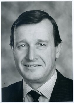 Man in striped shirt, dark jacket and tie