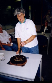 Shirley cutting a chocolate cake with 'Thank You Shirley'