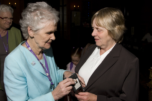 Marjorie West gives an attendee a headset for audio description