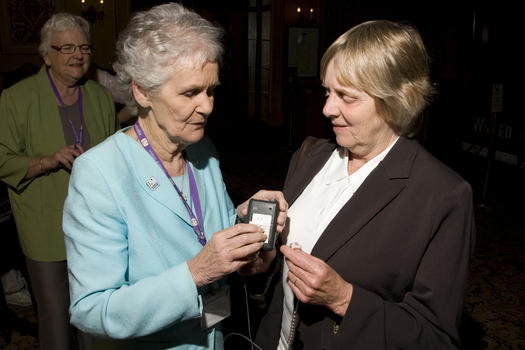 Marjorie West gives an attendee a headset for audio description