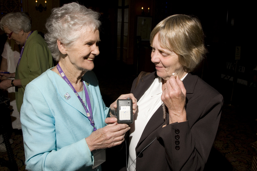 Marjorie West gives an attendee a headset for audio description