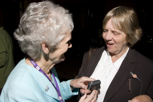 Marjorie West gives an attendee a headset for audio description