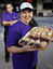 Gavin Strahran standing behind Rita Townsend-Booth, who holds a tray of baked sweets 