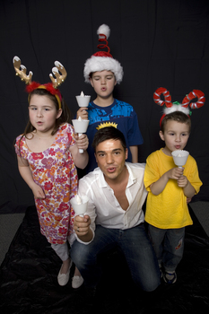 Kate, Nicholas and Jacob Law with Anthony Callea holding candles and wearing Christmas hats